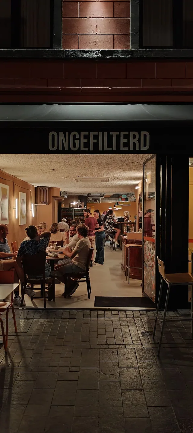 De gevel van Ongefilterd 's avonds, met zicht op de volle zaal